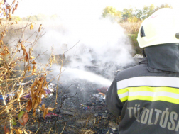 tűzoltó vízsugárral oltja a tüzet