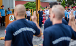 A tiszthelyettesek fogadalmat tesznek, sapkájukat levéve és kezüket eskühöz emelve. Előttük a rendezvény meghívottjai és az esküt előolvasó társuk látható.