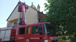 létráról avatkoznak  be a tűzoltók, bontják a tetőt