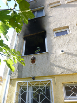 tűzoltó a kiégett konyha ablakában