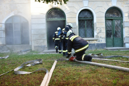 épületből füst áramlik ki, egységek térdelnek az épület bejáratánál